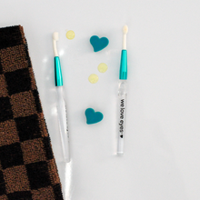 Load image into Gallery viewer, Two makeup brushes with teal handles on a light gray background with decorative hearts and a checkered fabric.