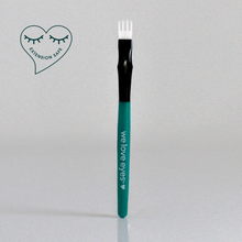 Load image into Gallery viewer, Eyebrow brush with green handle and black bristle head on a light gray background, featuring 'we love eyes' branding.