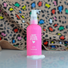 Load image into Gallery viewer, Pink bottle labeled 'we love eyes' with colorful leopard print fabric in the background