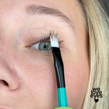 Load image into Gallery viewer, Person applying makeup with a brush near their eye, with 'we love eyes' branding.
