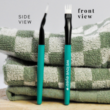 Load image into Gallery viewer, Two makeup brushes with teal handles and black bristles on a checkered towel.
