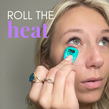 Load image into Gallery viewer, Woman applying a teal roller to her eye with text 'ROLL THE heat' on a gray background

